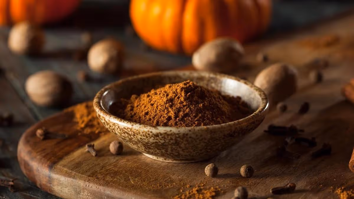 Mélange d'épices pumpkin spice dans un bol, avec noix de muscade, clous de girofle et cannelle.